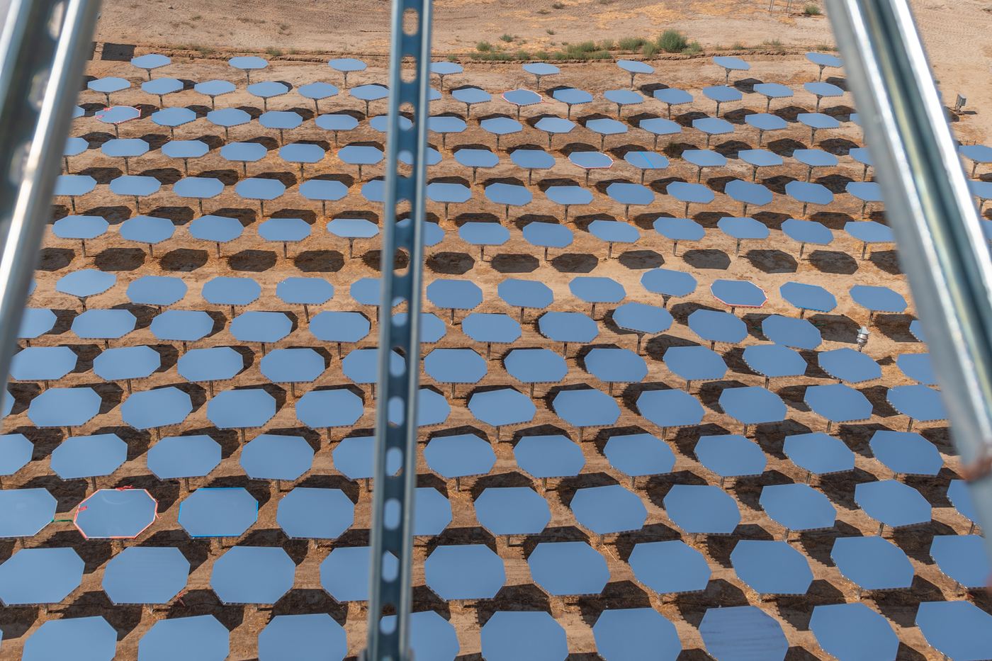 Rows of small heliostat mirrors seen from a tower platform