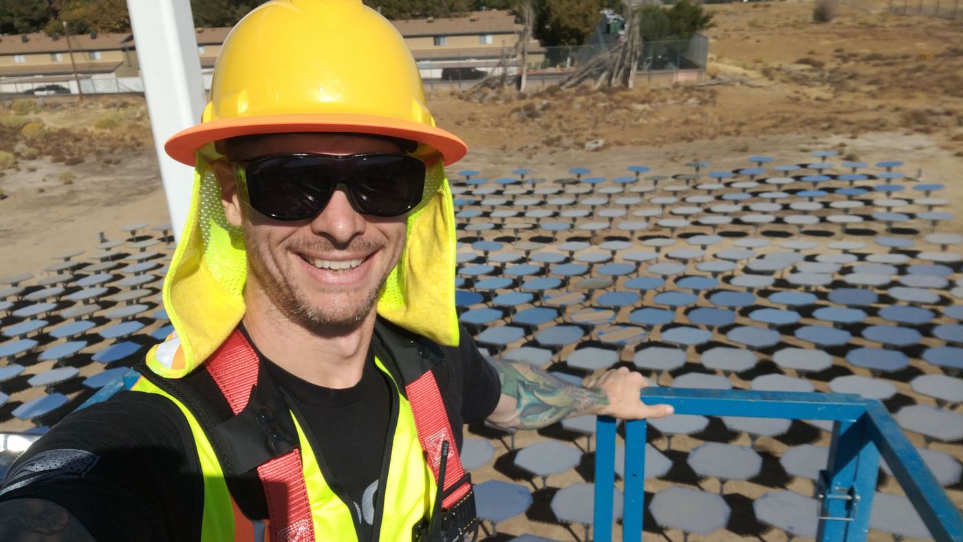 Steve in a hard hat and safety vest above a heliostat field